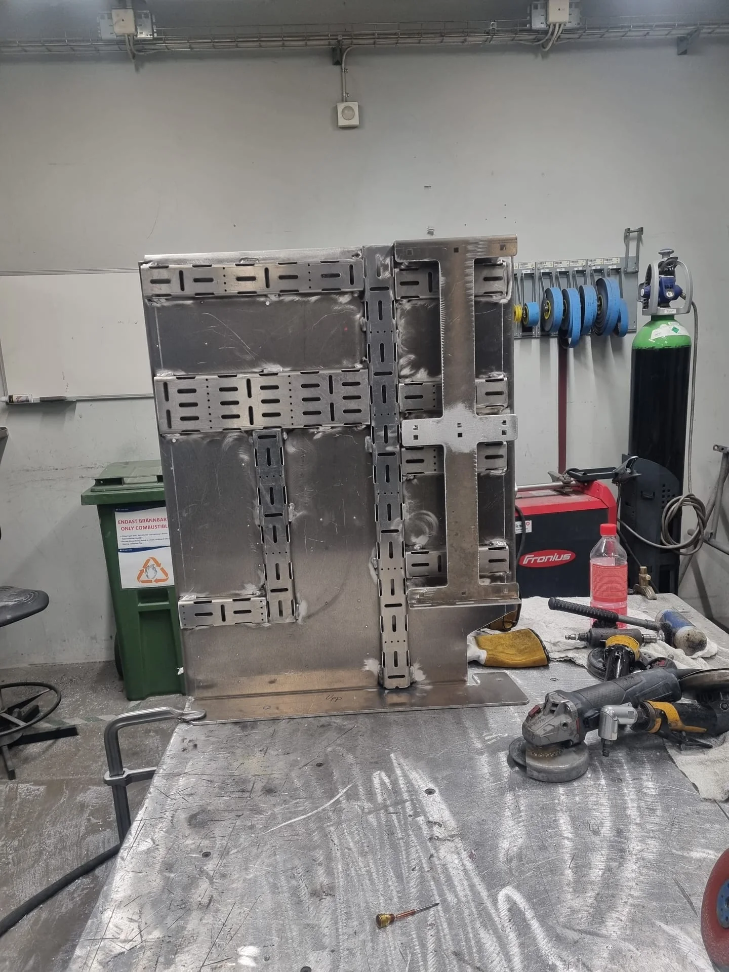 Aluminiumkonsol med kabelstegar på svetsbordet, med Fronius-svets bredvid